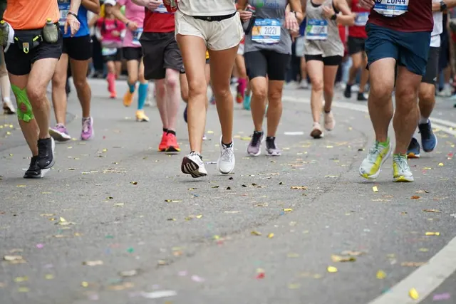 Runners' legs crossing confetti-covered pavement near a big-city marathon finish