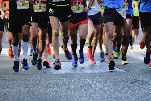 Close-up of runners' legs and shoes tightly packed together at a marathon start line