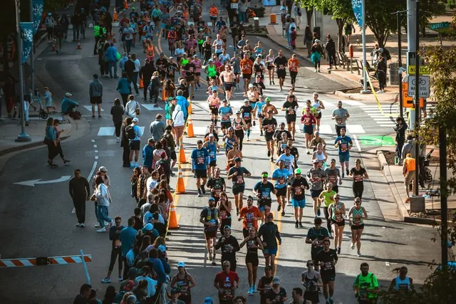 Aerial view of marathon runners on a tree-lined downtown street with banners and string lights